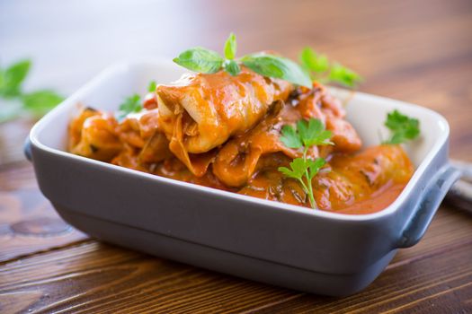 Traditional stuffed cabbage with minced meat and rice, served in a tomato sauce on a wooden table .