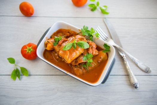 Traditional stuffed cabbage with minced meat and rice, served in a tomato sauce on a wooden table .