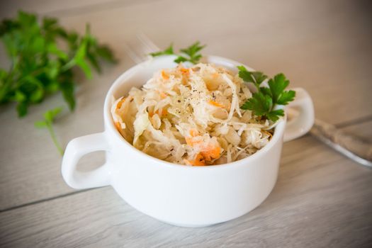 sauerkraut with carrots and spices in a bowl on a wooden table.