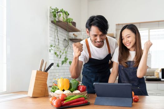 Happy couple preparing food together in kitchen at home ready to cook together.