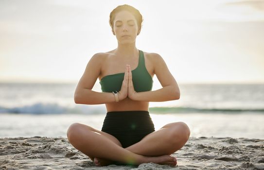 Woman, yoga and meditation on the beach in sunset for spiritual wellness, zen or workout in the outdoors. Female yogi relaxing and meditating for calm, peaceful mind or awareness by the ocean coast.