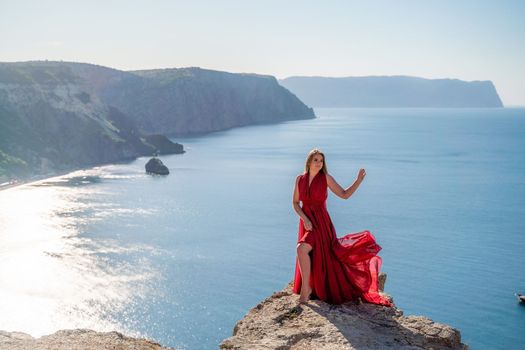 A woman in a red flying dress fluttering in the wind, against the backdrop of the sea