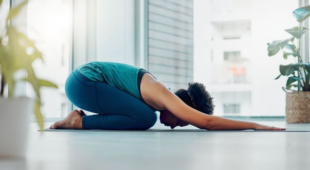 Yoga, child pose and wellness exercise of a black woman in a gym or health studio for pilates. Meditation, peace and relax female person doing a balance, zen and chakra workout for self care.