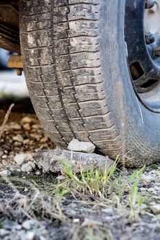 Stone under a car wheel in the grass close up