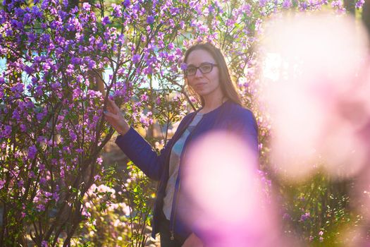 Woman travelling in Altai mountains on spring beautiful booming pink Rhododendron flowers background