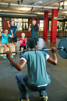 Winners are people who never quit. a man lifting weights while a group of people in the background watch on