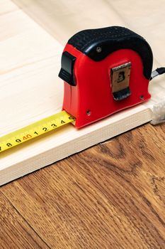 Measuring a wooden board with an yellow tape measure close up, copy space