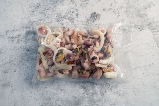 Pack of frozen seafood in hand on grey concrete backgound