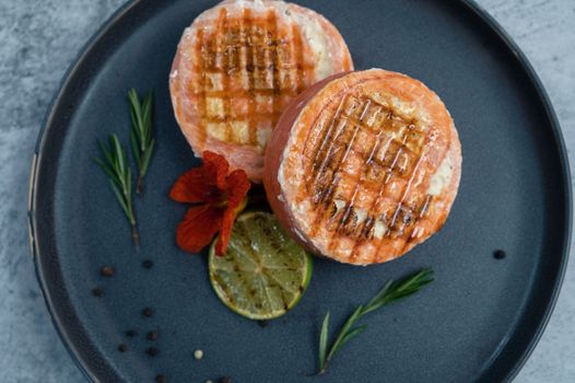 Grilled salmon roll with mozzarella. Decorated with greens lime and edible flower
