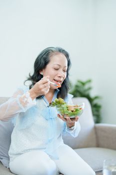 Portrait of an elderly Asian woman taking care of her health by eating salad