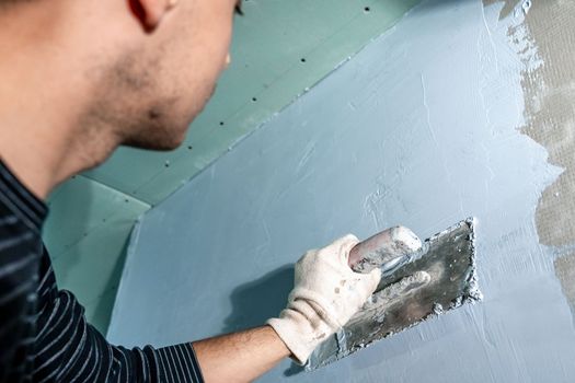 manual work with a trowel for waterproofing the wall.