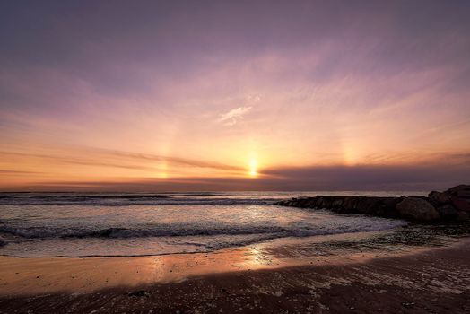 Rainbow sunrise on a deserted Mediterranean beach. Long exposure, warm colours