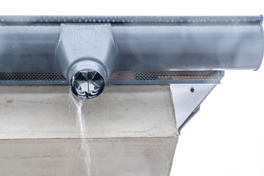 gutter with flowing rainwater on the roof of the building.