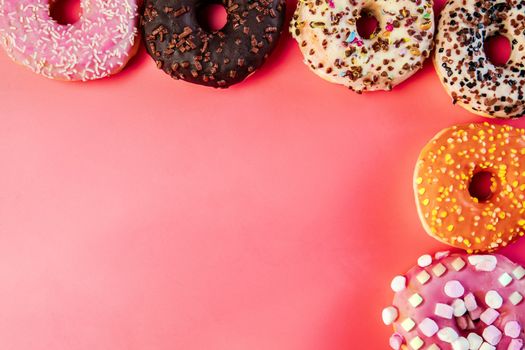 Donuts with icing on pastel pink background. Sweet donuts. top view assorted with various chocolate glazed and sprinkles, sugar sweets concept candy