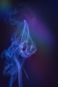 A vertical shot of smoke in colorfull backlight with a blue note