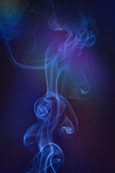 A vertical shot of smoke in colorfull backlight with a blue note