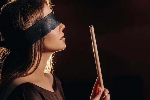 A girl with a blindfold and a cue in her hands in a billiard club.Russian billiards.