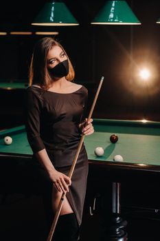 Masked girl in a pool club with a cue in her hands.