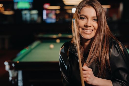 A girl with a cue in her hands is standing in a billiard club.Russian billiards.