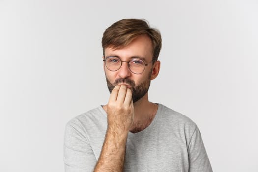 Close-up of handsome man in glasses giving a compliment, making chefs kiss sign, praising delicious food, standing over white background.