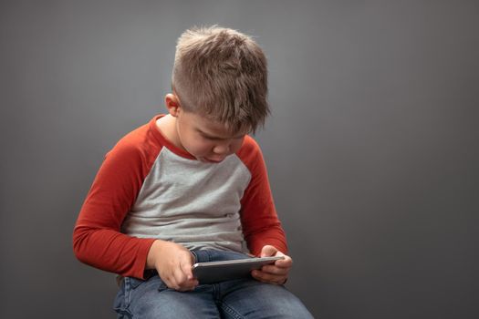 Preschool boy using mobile phone. Child in studio holds big smartphone speaking on it with friends online. Technology concept.