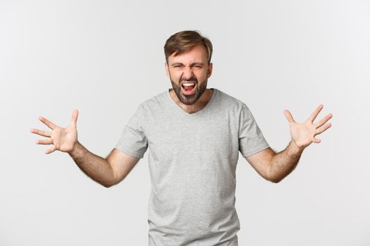 Portrait of angry bearded man, shouting and shaking hands frustrated, standing mad over white background.