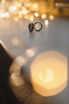 Wedding rings on blured bokeh glowing golden background. Symbol of love and romance on a textured glitter background with copy space for your greeting or congratulations.