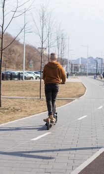 Young man riding electric scooter in urban background. Modern transport and lifestyle concept