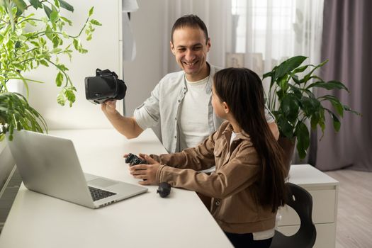 Little girl having fun time with her father using VR glasses at home for learning molecular structure. Homeschooling concept. Modern technology using by family.