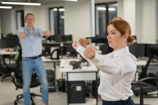 Three office workers warm up during a break. Employees do fitness exercises at the workplace