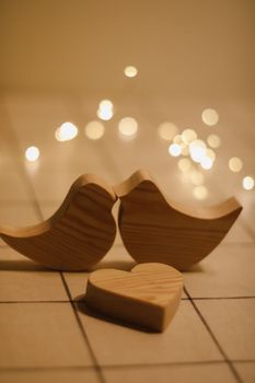 two wooden birds and heart made by bokeh lights background. Valentines day, Easter, Wedding card with wooden figures of birds, home decor.