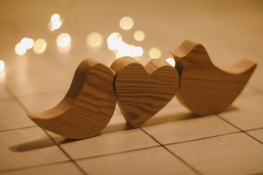 two wooden birds and heart made by bokeh lights background. Valentines day, Easter, Wedding card with wooden figures of birds, home decor.