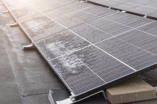 Solar panel in winter. Solar panels are covered with snow on the roof of the building, the use of modules in difficult weather conditions. Electricity production in winter, with copy space.