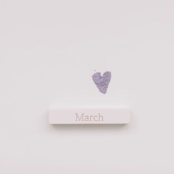 The word March on wooden brick on a white background top view.