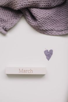 The word March on wooden brick on a white background top view.