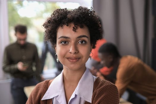 Successful businesswoman standing in creative office and looking at camera while smiling