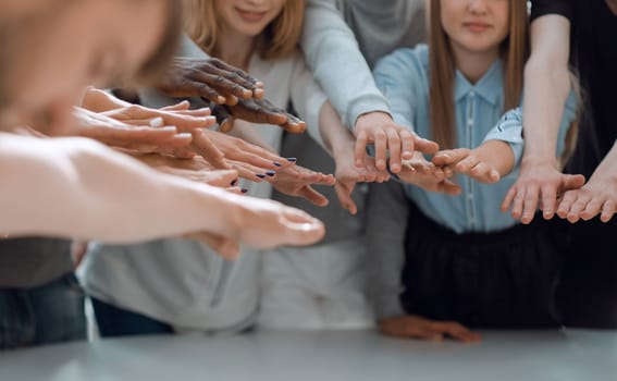 close up. a group of smiling young people joining their hands together