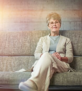 vision, age and people concept - portrait of happy senior woman in glasses sittin on sofa at home