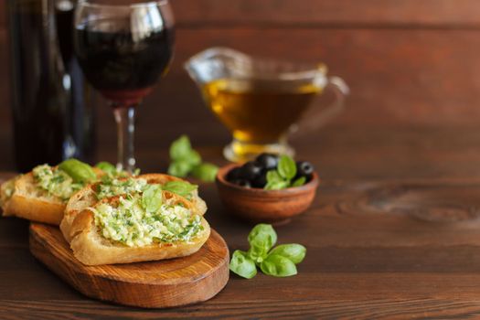 Delicious bread with garlic, cheese and herbs, red wine and olives on a wooden table.Copy space