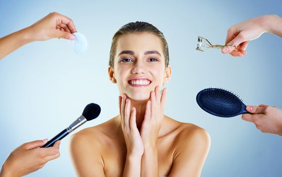 Everything I need to look fabulous. Studio portrait of a beautiful young woman with an assortment of beauty tools around her against a blue background