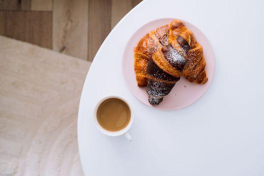 Flat lay cup of cappuccino and croissants on white coffee table in room