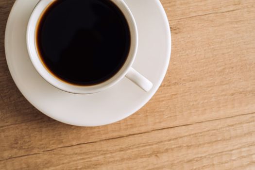 Flat lay cup of black coffee with a saucer on wooden table