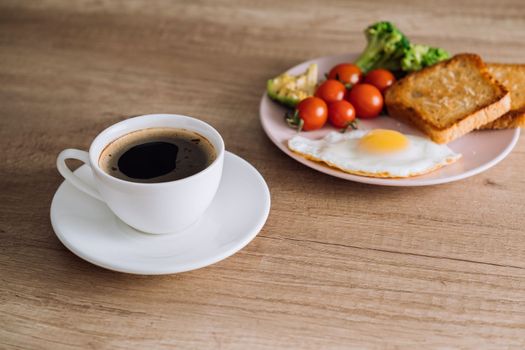 Cup of black coffee with homemade breakfast on wooden table