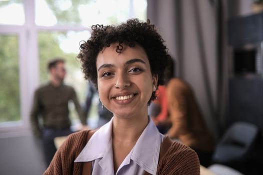 Successful businesswoman standing in creative office and looking at camera while smiling
