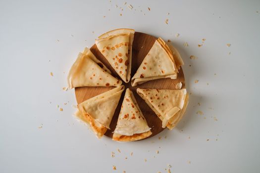 Flat lay of crepes laid out in triangles in a circle on wooden board