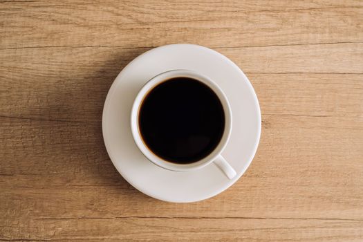 Flat lay black coffee in a white cup with a saucer on wooden table