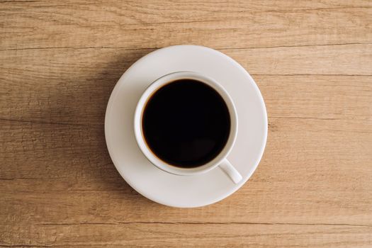 Flat lay black coffee in a white cup with a saucer on wooden table