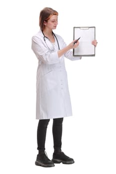 Attractive female doctor in a lab coat displaying a blank clipboard in front of her chest and pointing to it with a pen isolated on white background