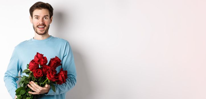 Romantic boyfriend bring beautiful bouquet of red roses on valentines day, having date with girlfriend, saying I love you, standing passionate on white background.