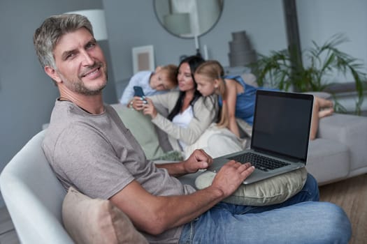 portrait of father on sofa, against the background of her happy family at home